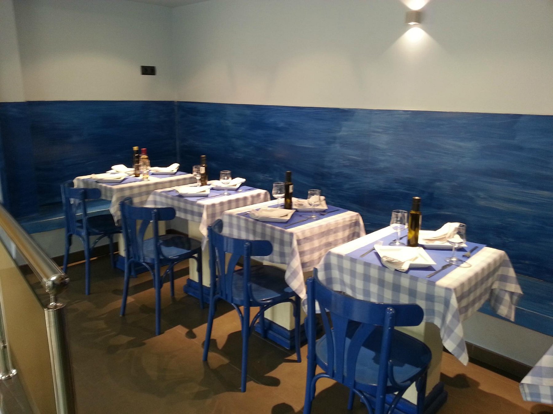 Comedor con la pared azul pintada y mesas con mantel de cuadros