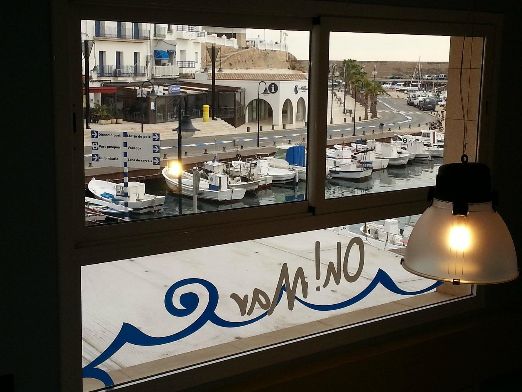 Ventana con el logotipo de Oh! Mar y el puerto al fondo